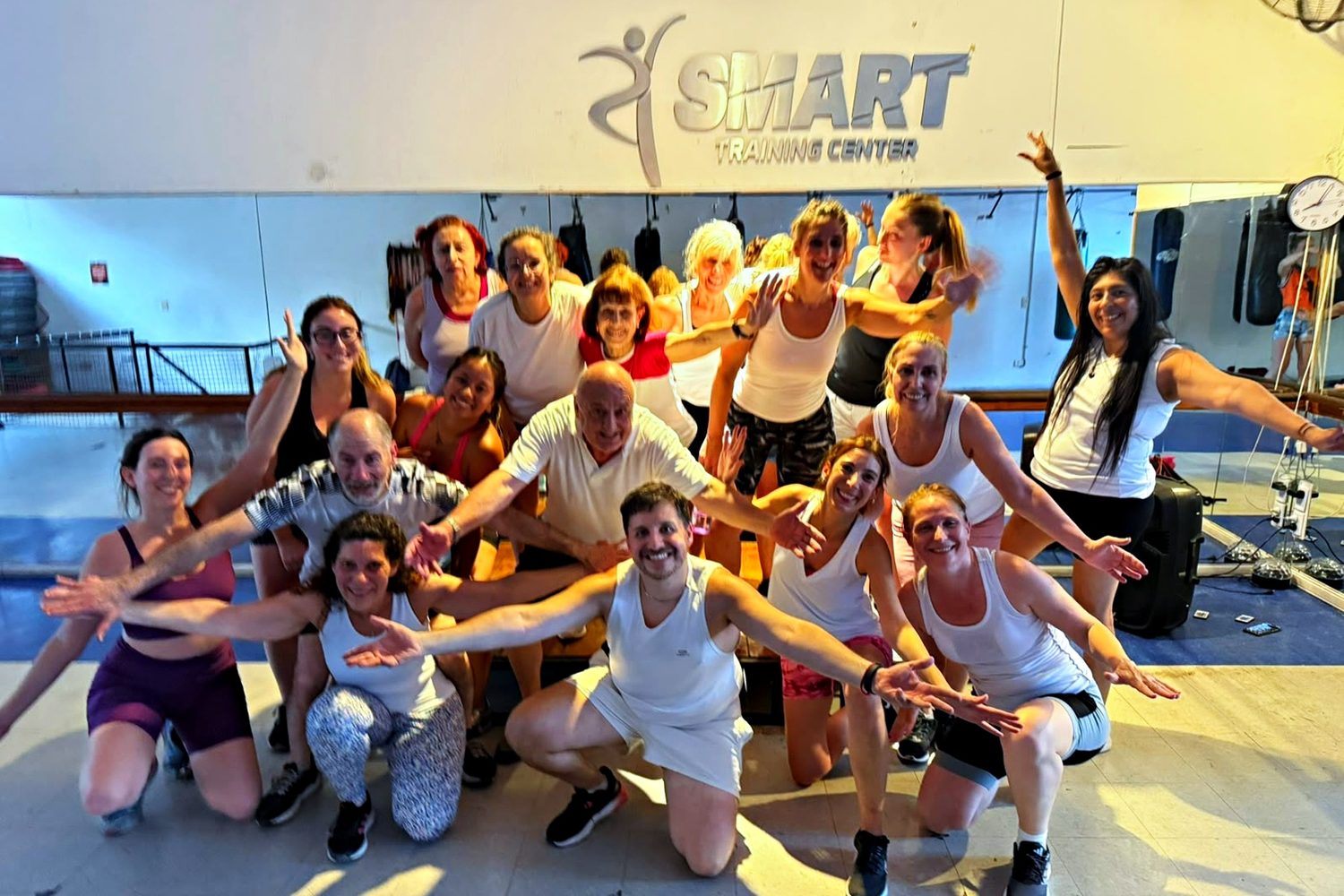 La clase entera, de blanco y con los brazos abiertos, bajo el cartel de Smart Training Center